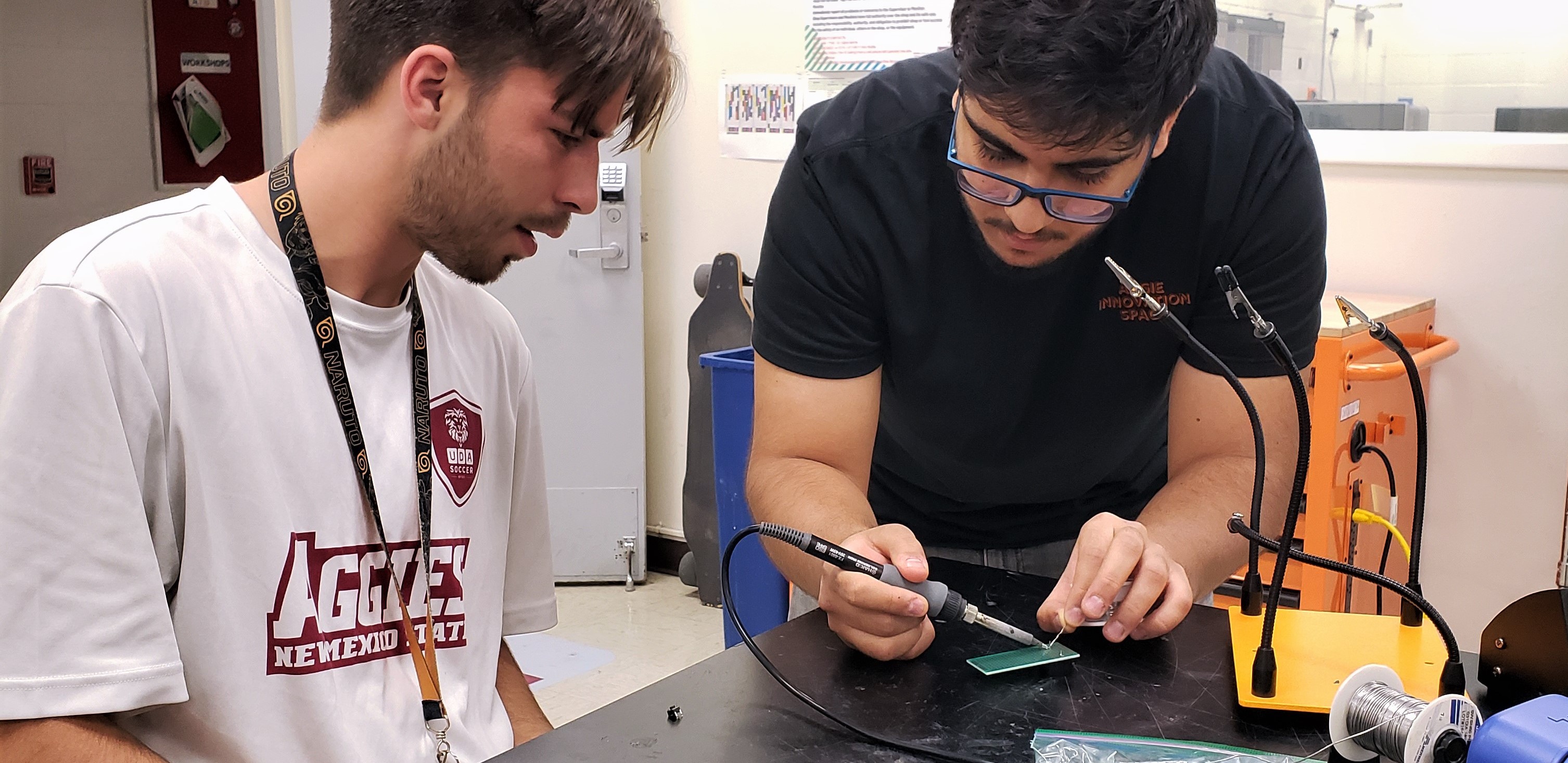 AIS student employee, Hasan Al-Shammari, assisting a student during the soldering workshop.